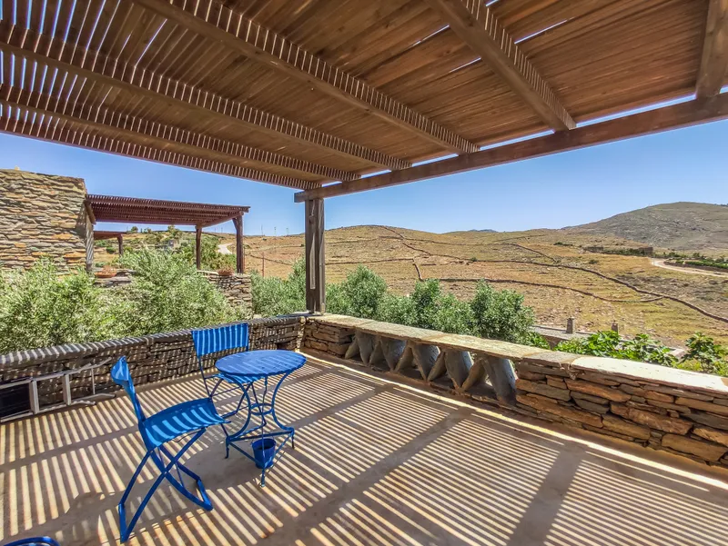 Pergola terrace with blue chairs and the hill and bay beyond