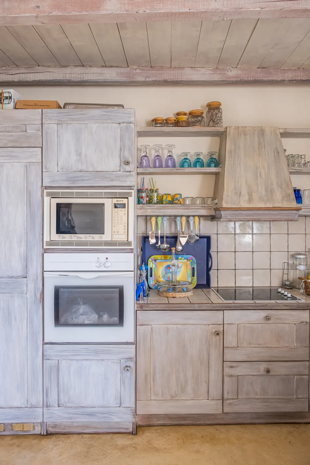 Close view of the kitchen tower with limewashed wood doors housing the oven, microwave, and storage