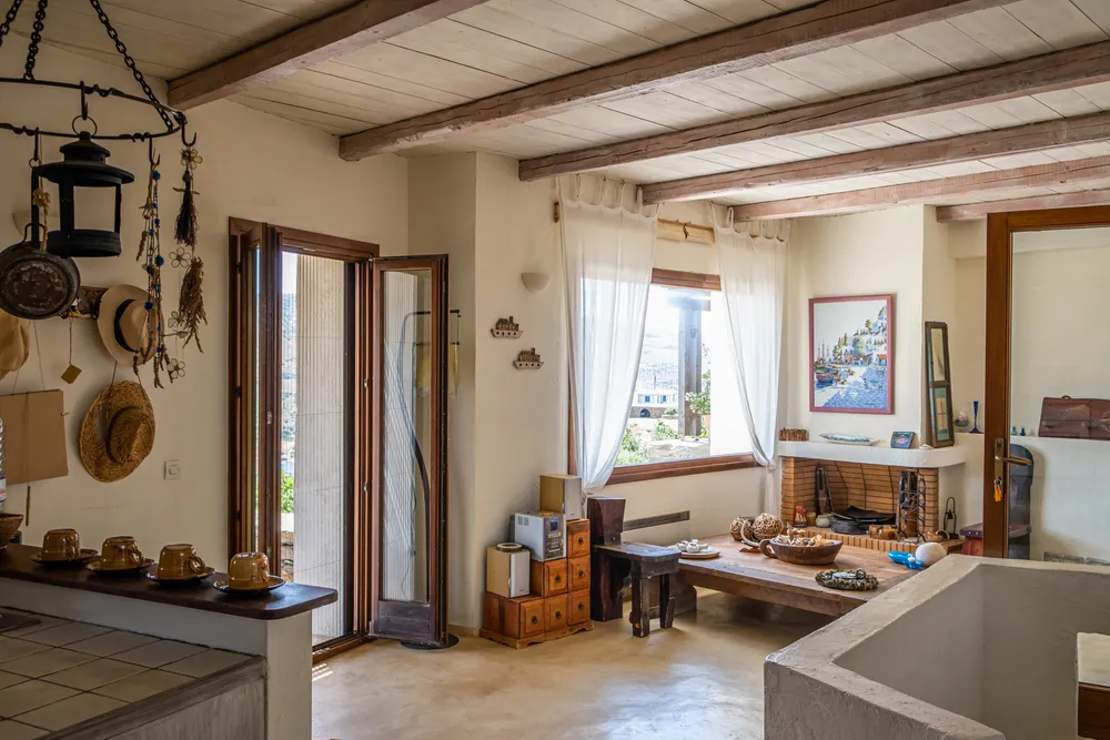 Open living area with white-painted wood-beam ceiling, lantern pendant, and view through to the garden door