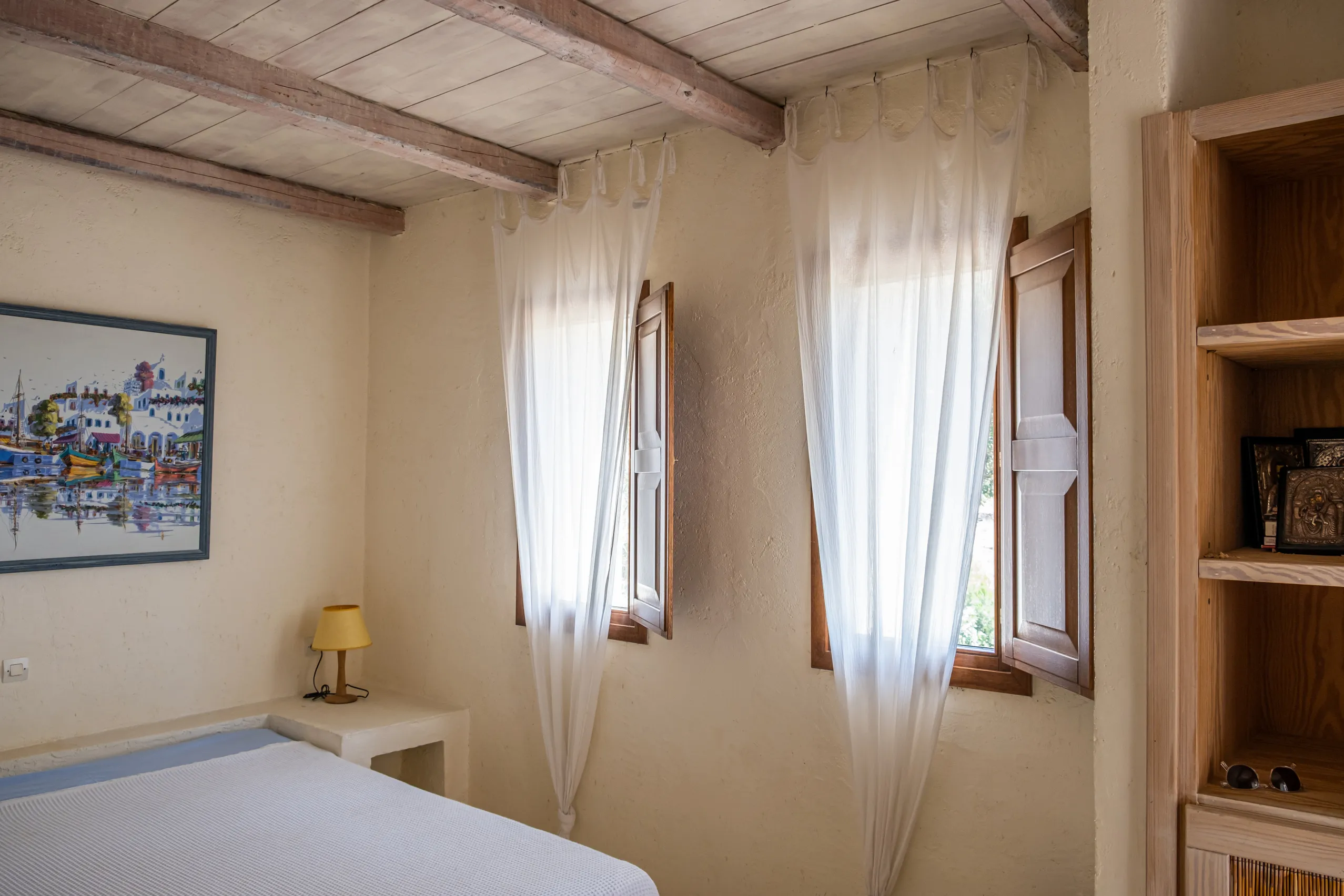 Master bedroom with stone walls and warm afternoon light at Zephyros Stone Villa, Kea