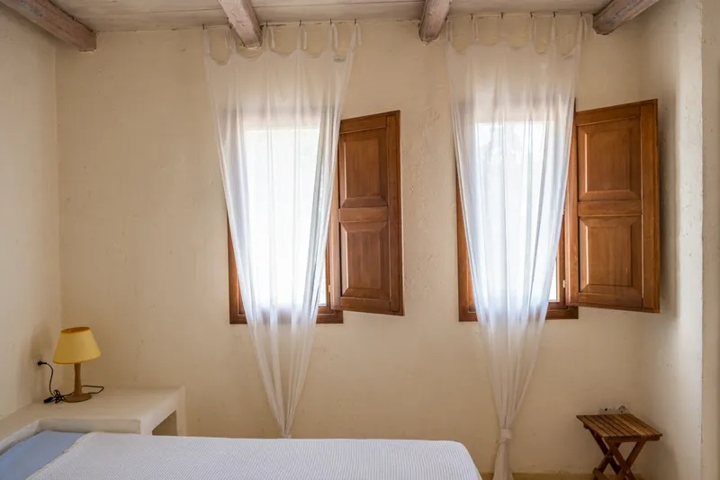 Master bedroom detail showing wooden ceiling beams and artisan headboard